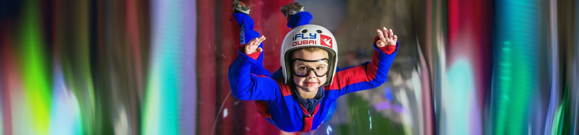 An instructor guiding a first-time flyer inside the iFly Dubai wind tunnel
