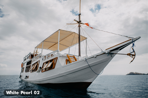 Traditional wooden phinisi sailing ship anchored in the clear water of Labuan Bajo