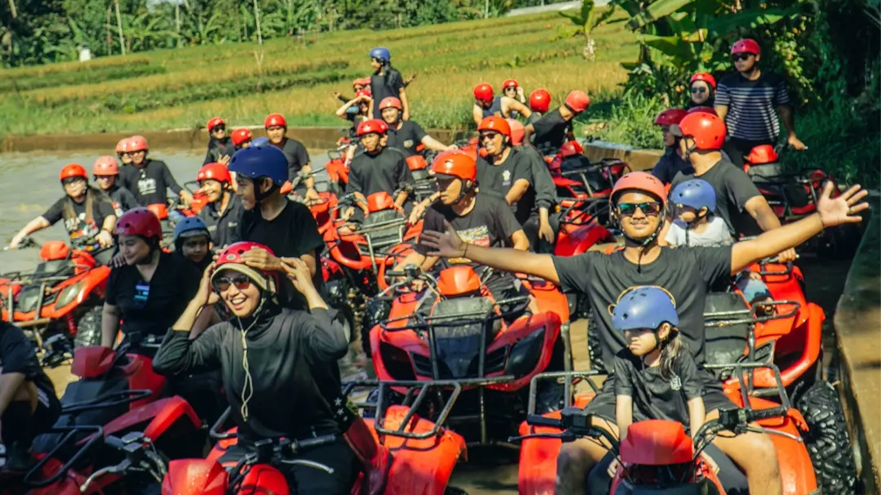Riders on all-terrain quad bikes following a muddy jungle trail near Ubud, Bali