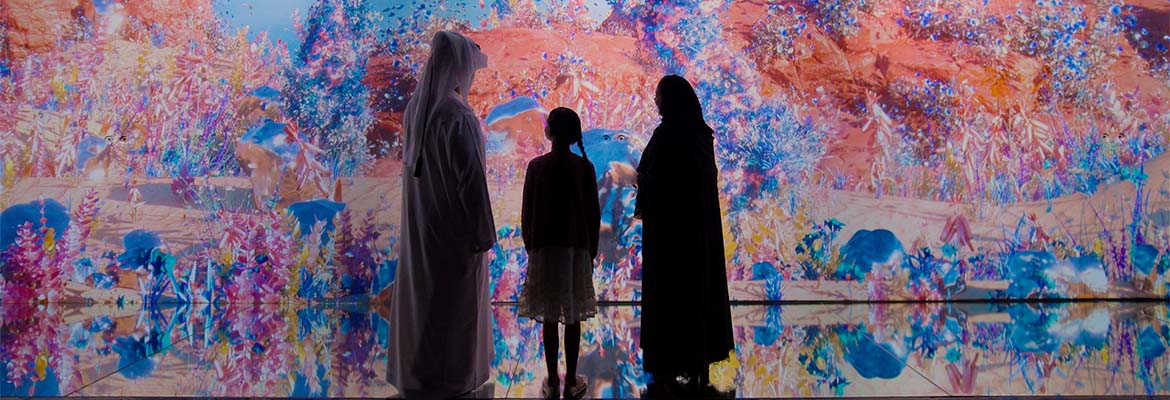Visitors walking through a glowing projection-mapped room at AYA Universe in Dubai