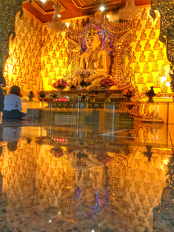 Seated Buddha statue in a gold-decorated shrine hall in Balestier